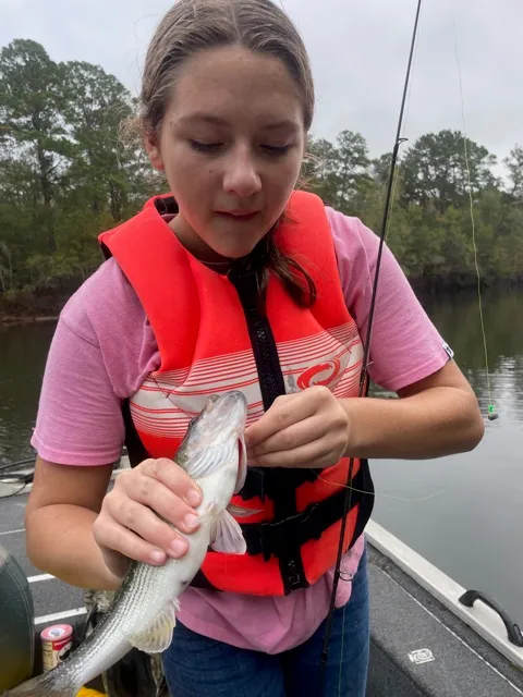 A young girl proudly holding a fish she caught on the lake