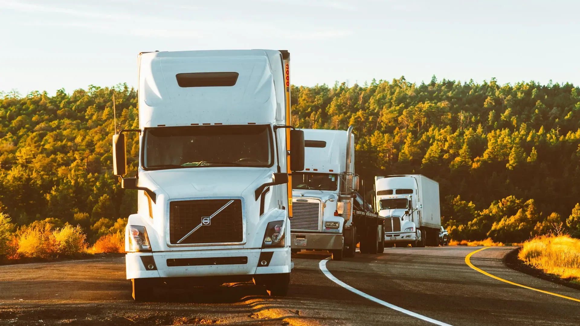 Semi trucks on a highway through a forested landscape